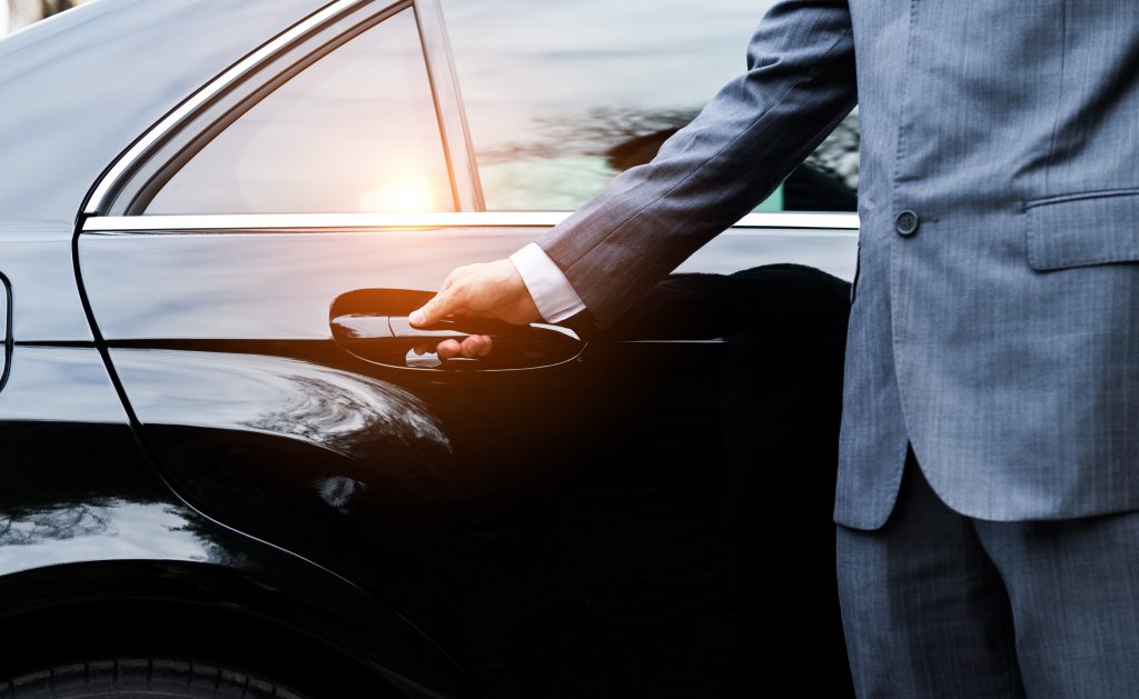 Chauffeur opening a black limousine door
