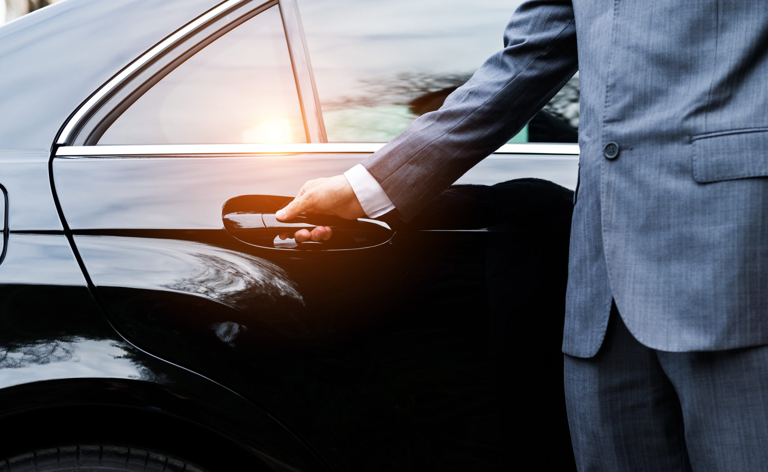 Chauffeur opening a black limousine door